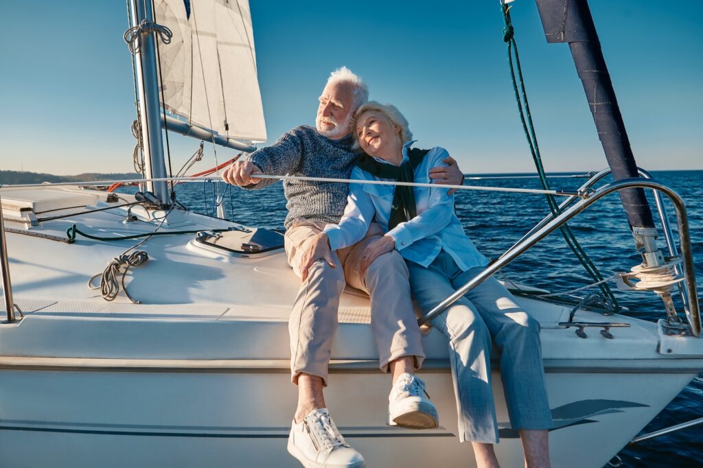 Enjoying sailing. Happy lovely senior family couple hugging and relaxing on a sail boat or